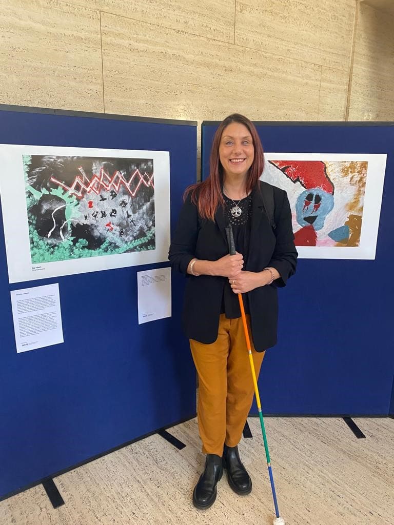 Nina in front of her artwork which interprets her hallucinations from Charles Bonnet Syndrome